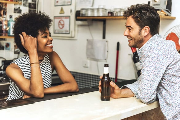 Side view of young man drinking beer in bar and flirting with bartender - signs a virgo man likes you