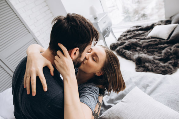 The couple kissing on the bed in a light room - Virgo man romance guide