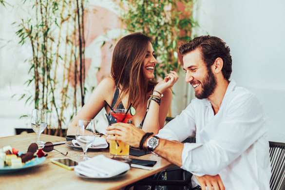 Young couple sitting in the outdoor bar and drink cocktails - signs that a virgo man is definitely interested in you