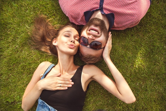 couple in love in sunglasses lying on the grass and laugh - What is the Best Way to Date a Virgo Man